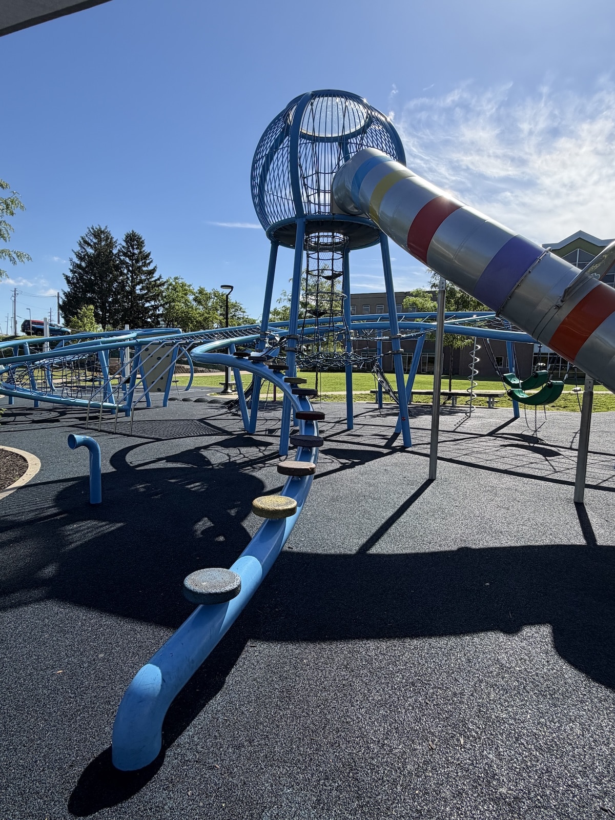 Tall blue climbing dome and striped tube slide at Colts Canal Playground in downtown Indianapolis