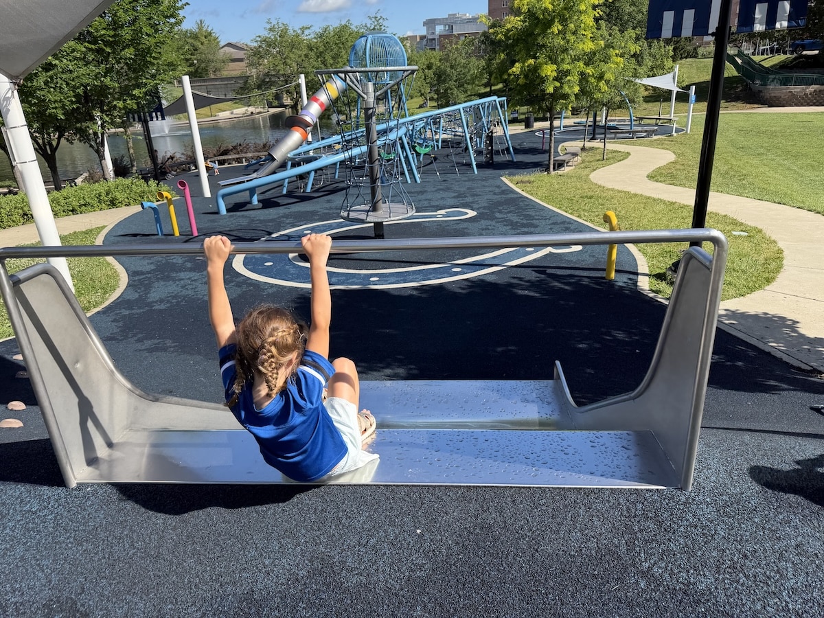 Child going down the small hillside slide at Colts Canal Playground in Indianapolis
