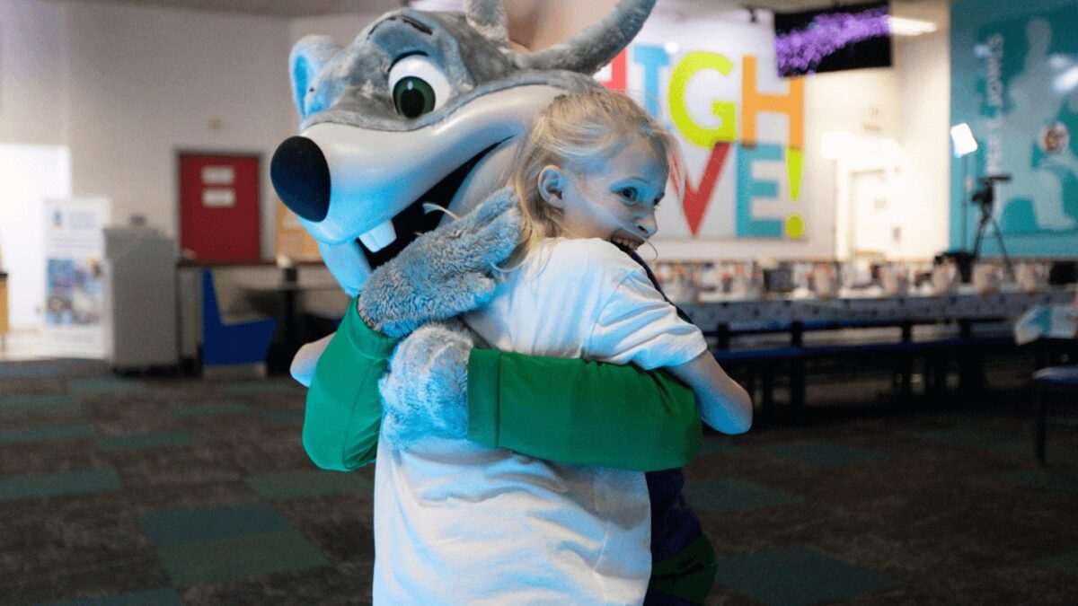 A child hugging Chuck E. Cheese during a Sensory Sensitive Sunday
