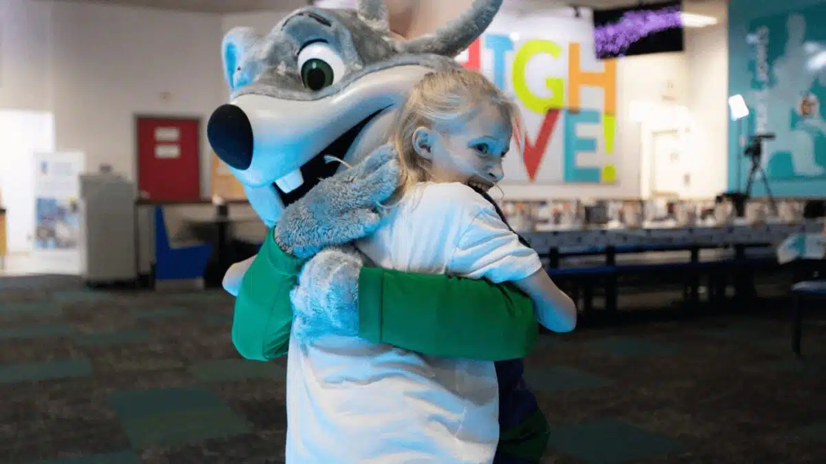 A child hugging Chuck E. Cheese during a Sensory Sensitive Sunday