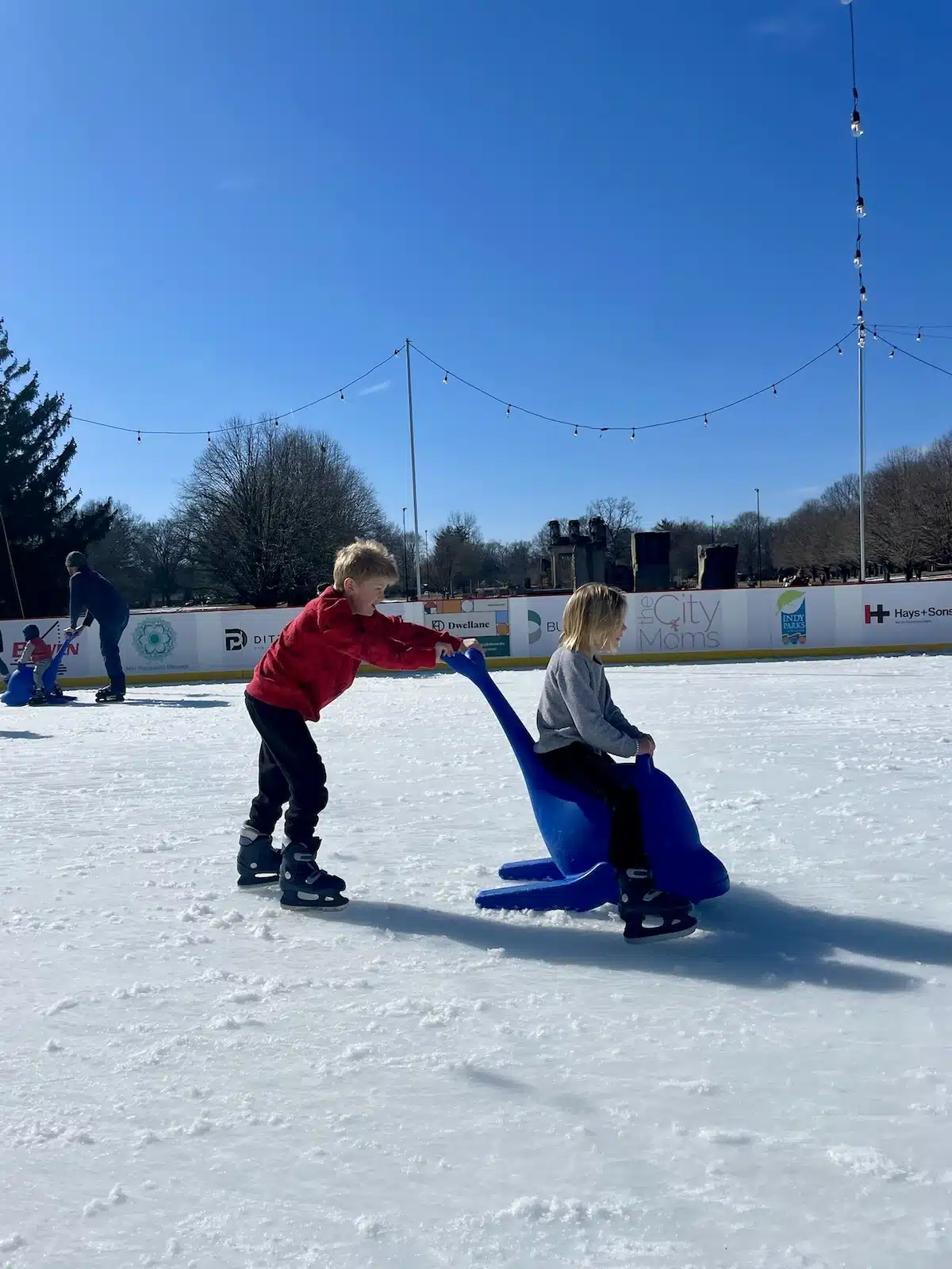 boy pushing girl on whale skate aid
