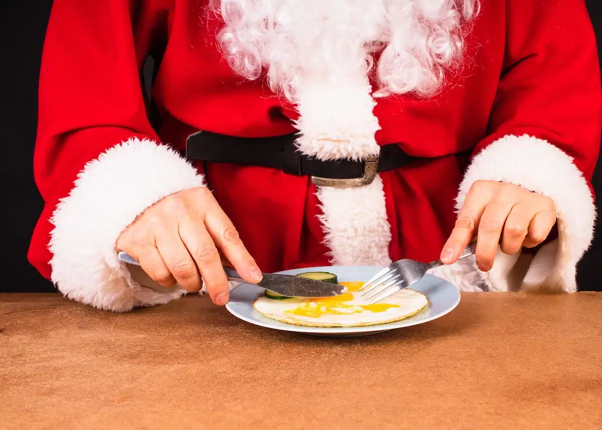 Santa eating breakfast in Indianapolis. Santa Claus in a traditional red costume sits at the table and eats a scrambled eggs.