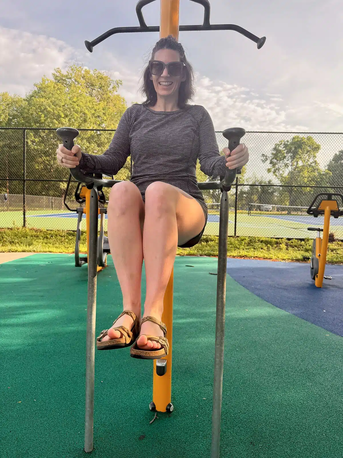 Parent using outdoor fitness equipment beside Frederick Douglass Playground
