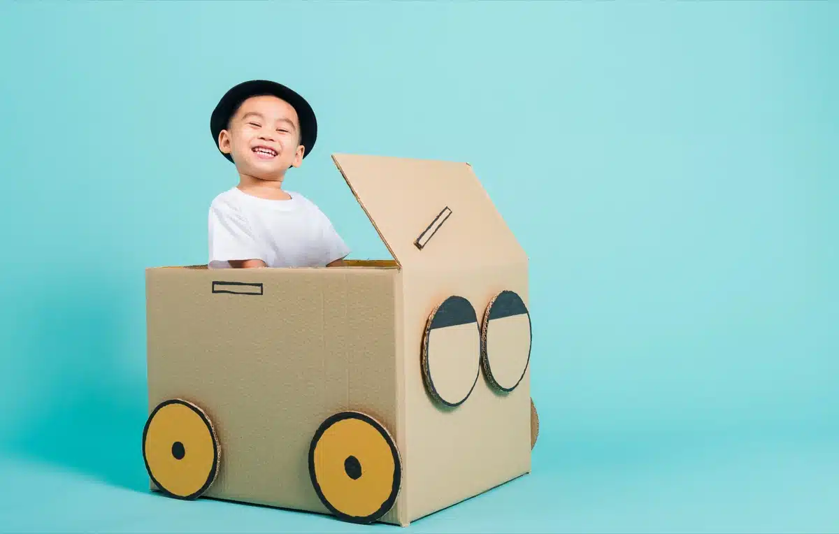 Boy driving a homemade cardboard box car