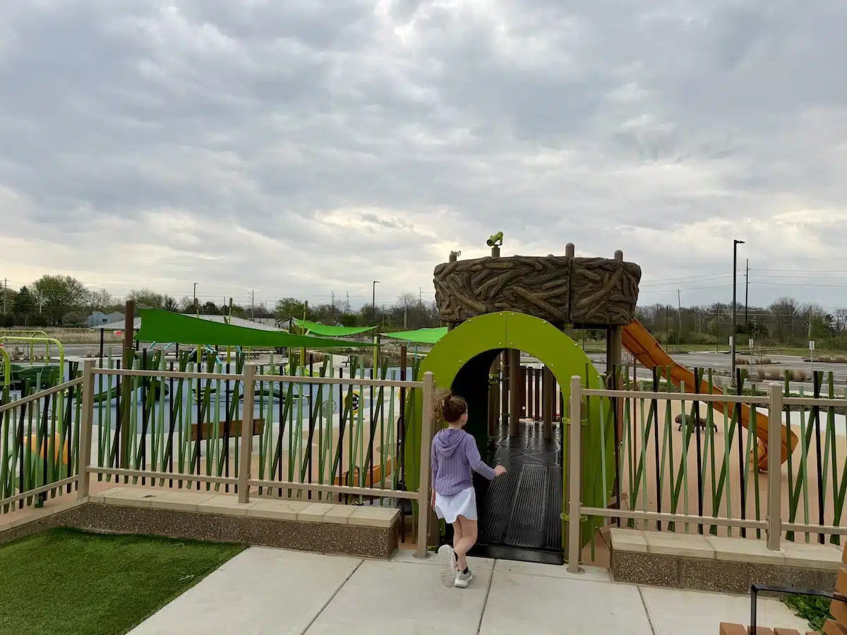Girl running into a playground tunnel at Grassy Creek Park