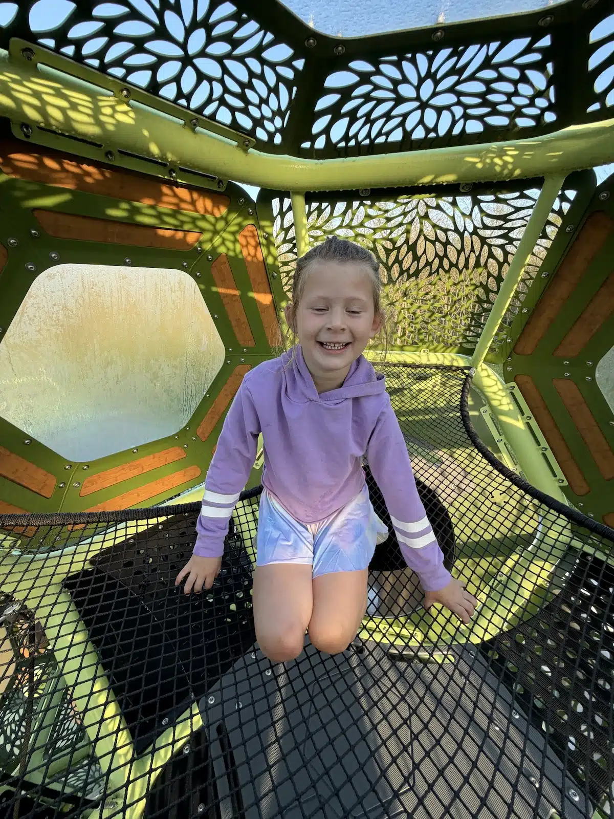 Girl playing inside the high treetop dome structure at Meadowlark Park in Carmel