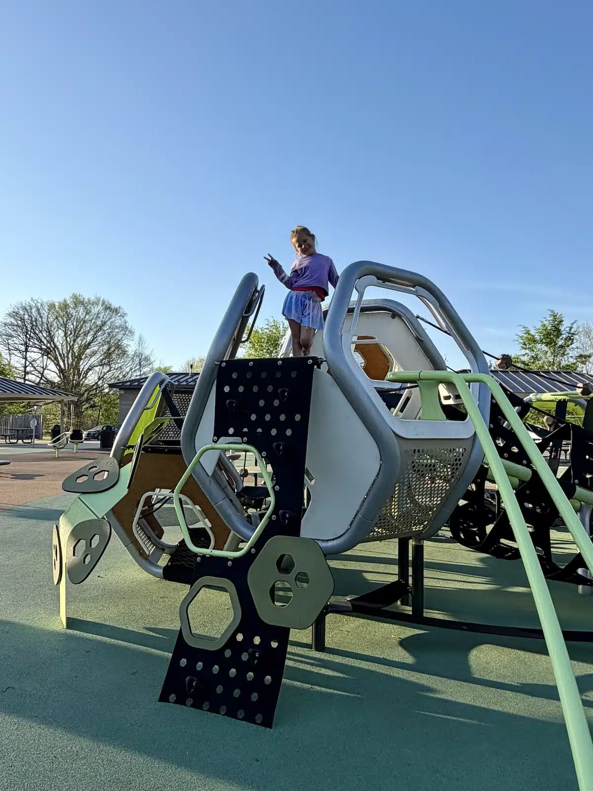 Girl sitting on top of the smaller play structure at Meadowlark Park playground