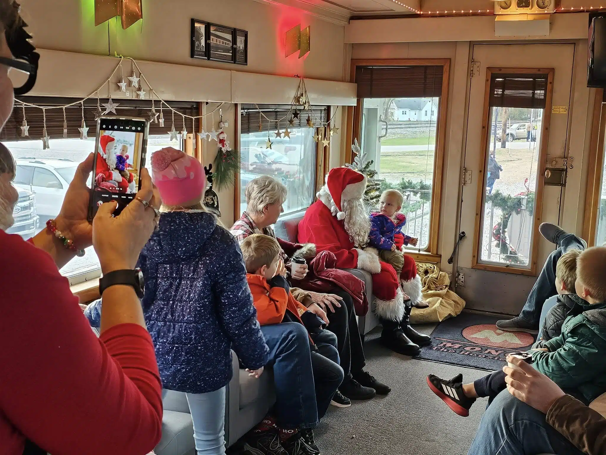 10 Best Holiday Train Rides in Indiana (2025) 7 Santa Train, santa talking to kids on the back of the train.