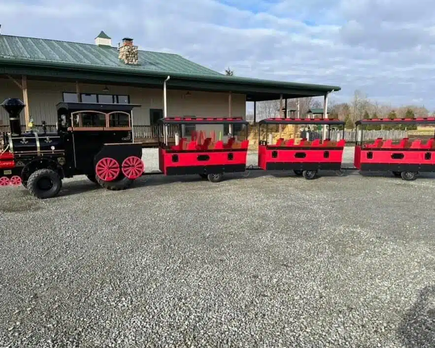 Glimmer Lights at Piney Acres: Train Rides, Santa and Holiday Lights 2 The Piney Acres Express trackless holiday train driving through glowing Christmas lights during Glimmer Lights at Piney Acres Farm