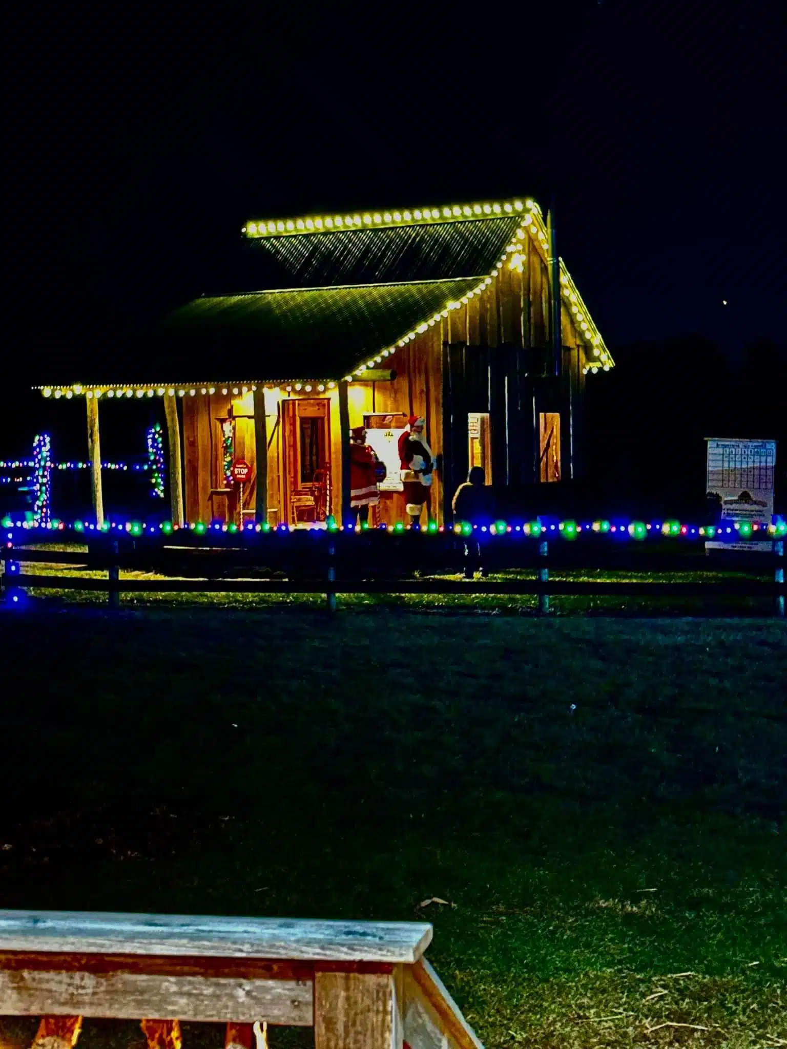 Glimmer Lights at Piney Acres: Train Rides, Santa and Holiday Lights 3 Santa greeting families on the porch of his rustic cabin at Piney Acres Farm during Glimmer Lights