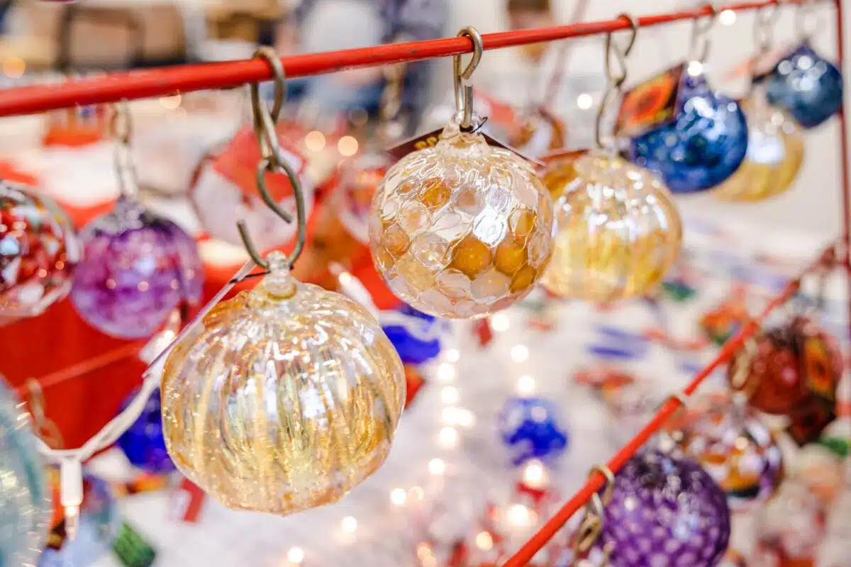 Handmade glass ornaments hanging on a display rack at the Indy Art Center Winter Art Sale