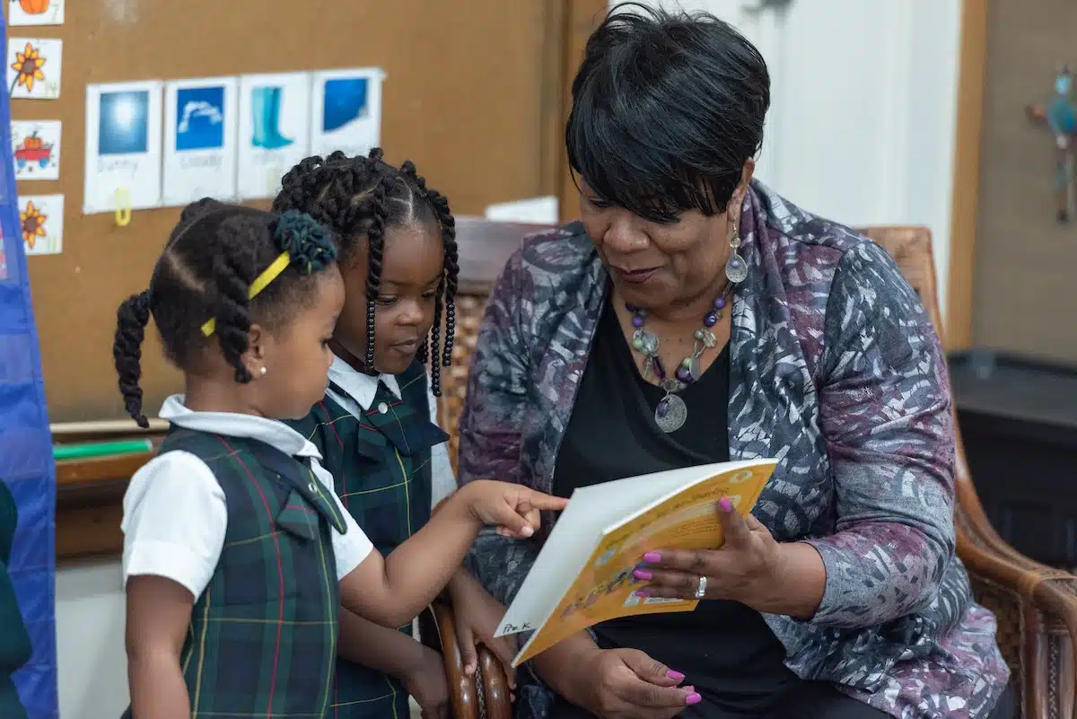 Pre-K students sharing a picture book with their teacher at The Oaks Academy