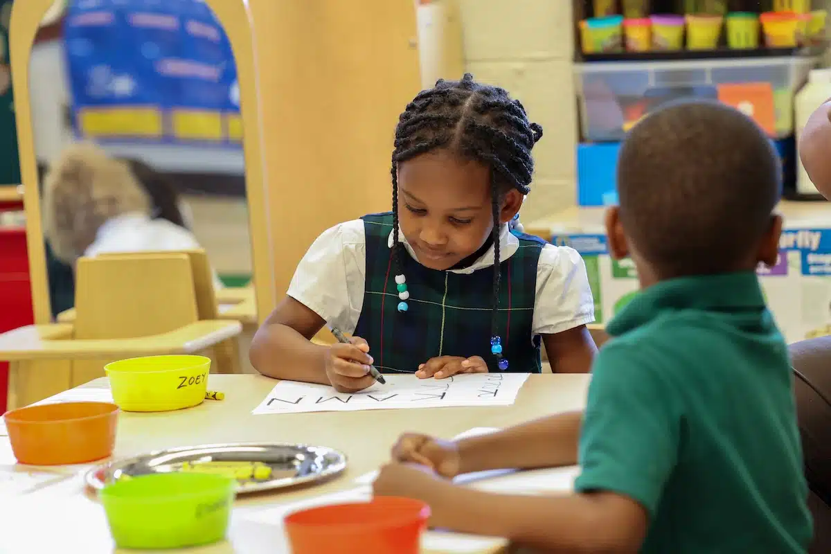 Pre-K students practicing letters on worksheets in the classroom at The Oaks Academy