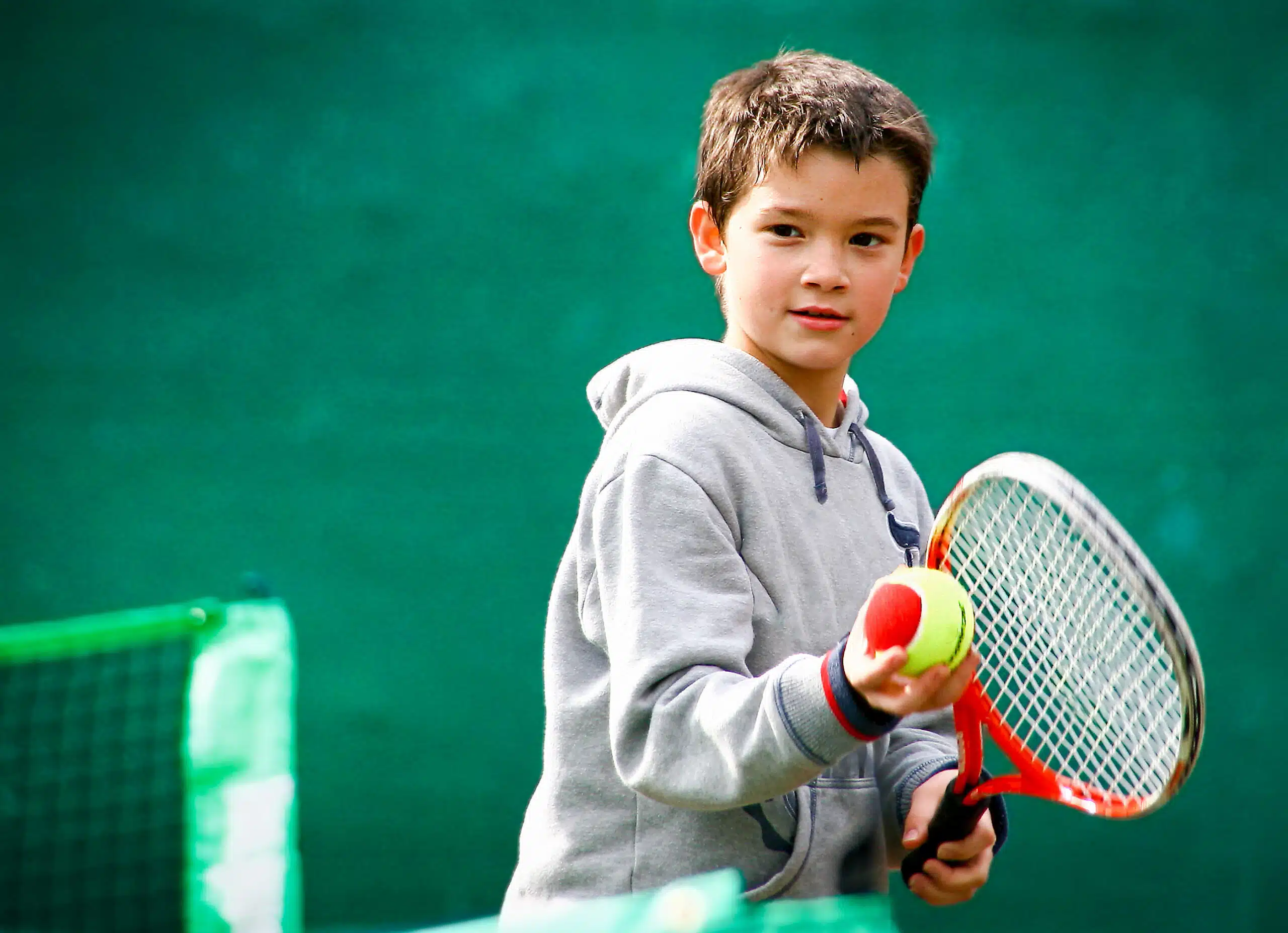 Young child holding a red tennis ball at the USTA Midwest Tennis Center in Indianapolis