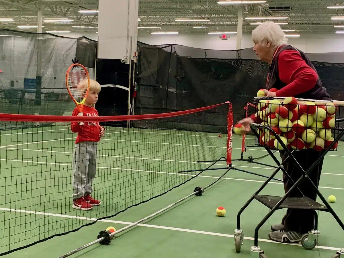 Barbara Wynne teaching tennis to her grandchildren on an outdoor court