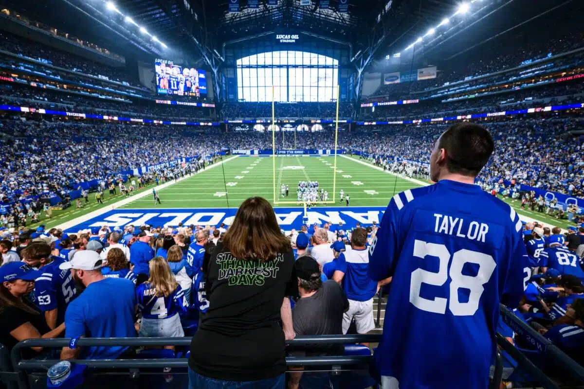 Fans in Colts jerseys watching a game from the stands at Lucas Oil Stadium