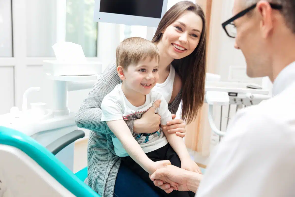 A mother and her young son talk with a dentist at a dental office