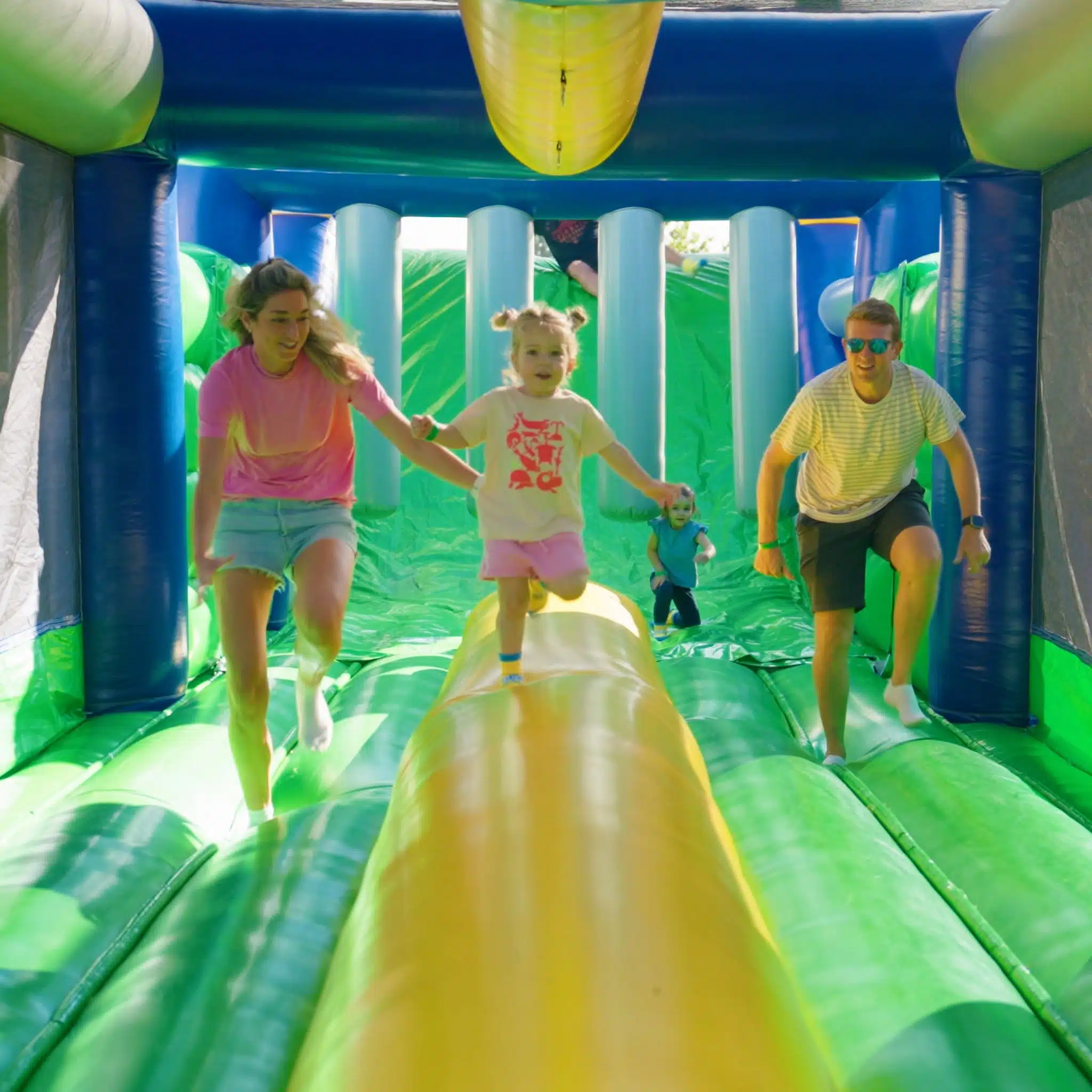 Giant 1,000-Foot Inflatable Obstacle Course Coming to Zionsville 2 Kids running through a green and blue inflatable section of the Tuff Nutterz obstacle course