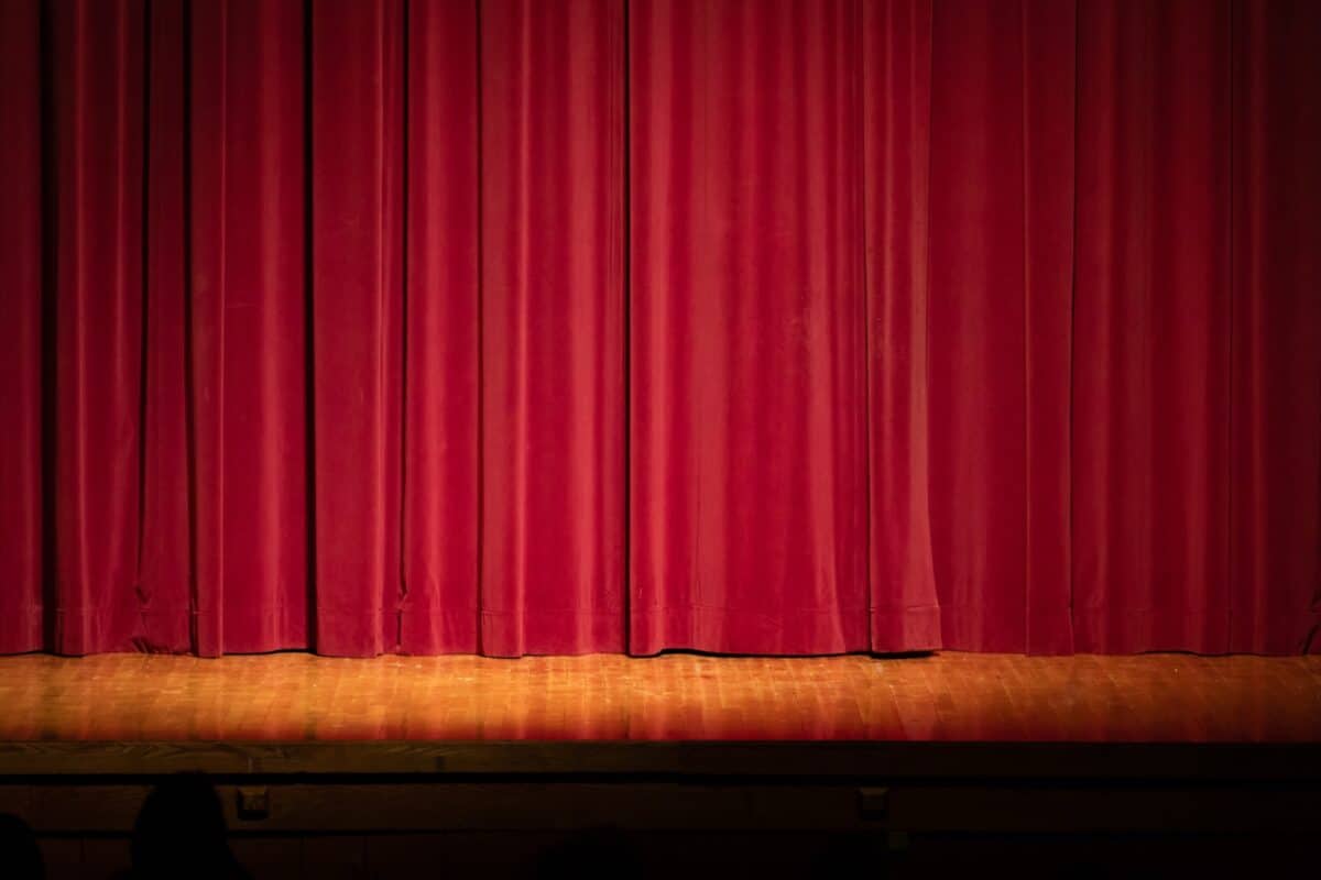 A closed red stage curtain before a performance