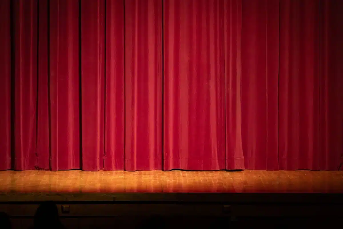 A closed red stage curtain before a performance