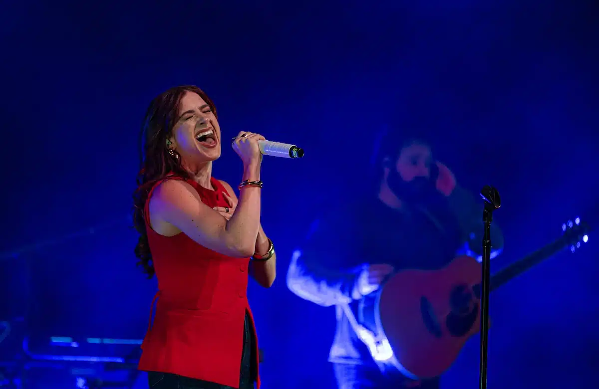 A singer performing under blue stage lights at Hendricks Live!