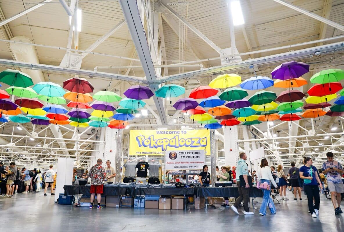 Shoppers on the show floor at a trading card show under colorful umbrellas