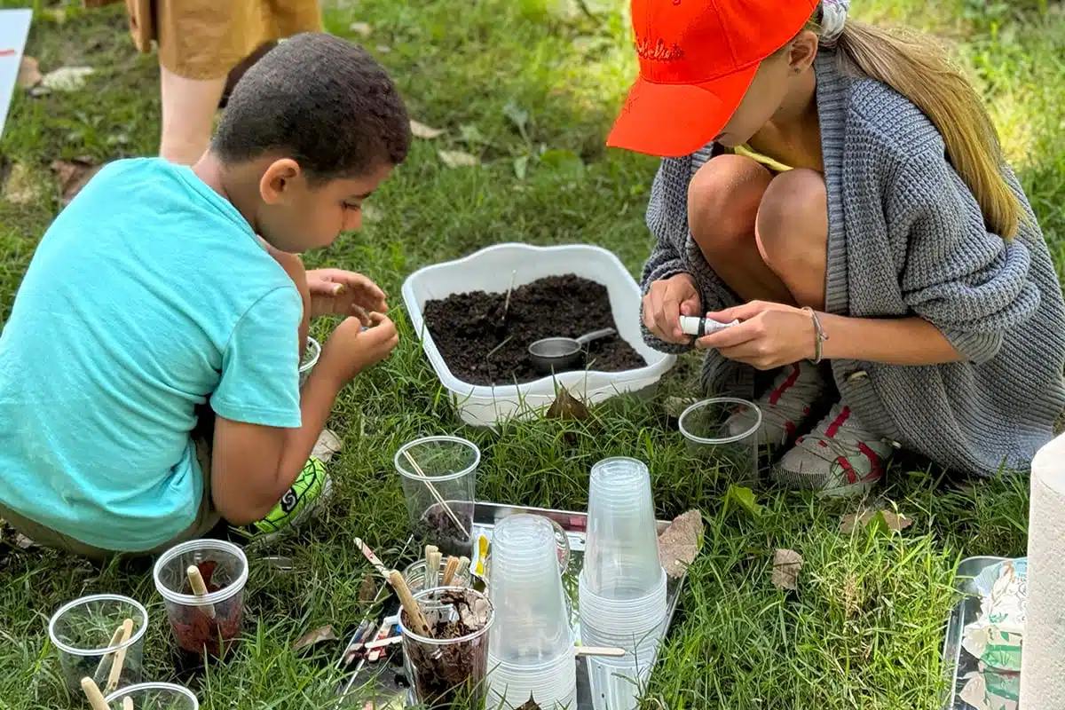 A child and an educator working with soil samples outdoors at Conner Prairie