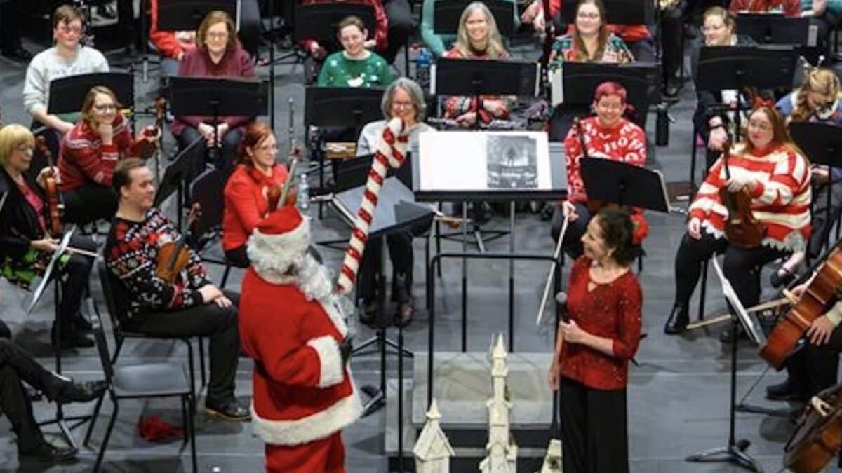 Santa conducting the Hendricks Symphony on a stage decorated for the holidays