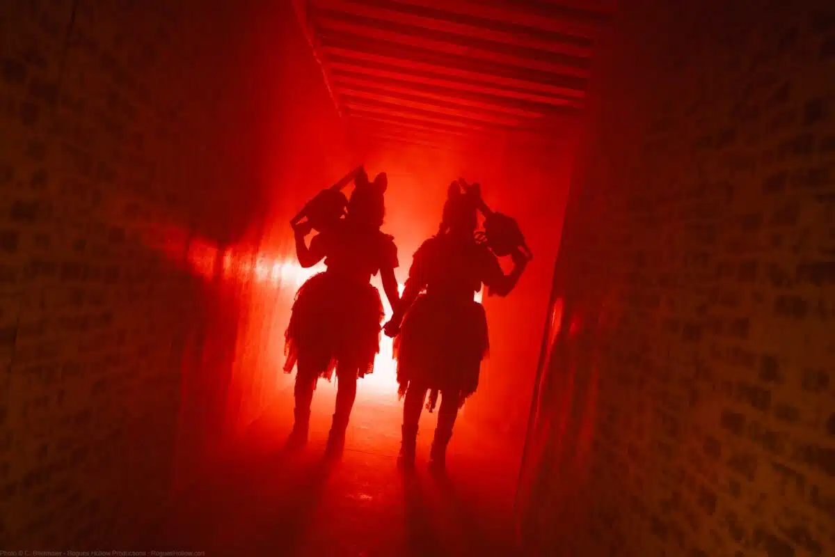 Two costumed figures silhouetted in a red-lit hallway at Indiana Fear Farm