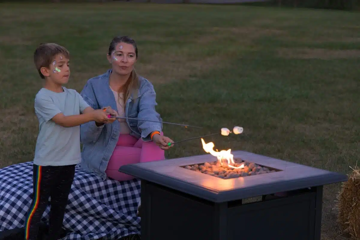 A mother and son roasting marshmallows over a fire pit at Brownsburg Parks’ Mother and Son Bonfire
