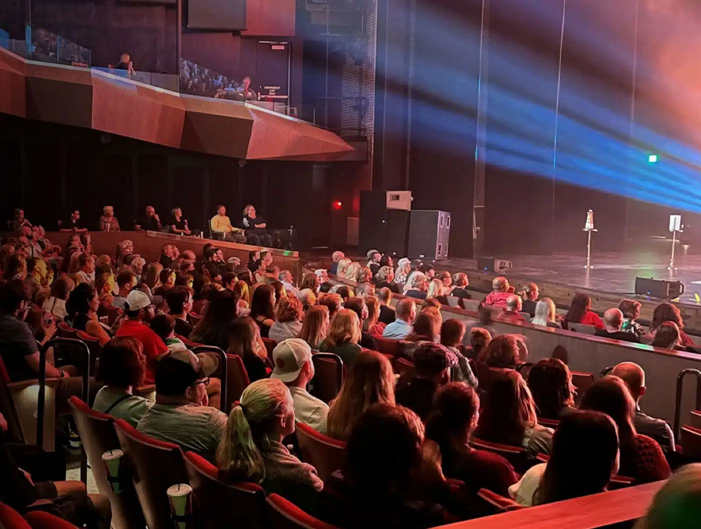 Audience in red seats facing the lit stage inside the theater at Hendricks Live! in downtown Plainfield
