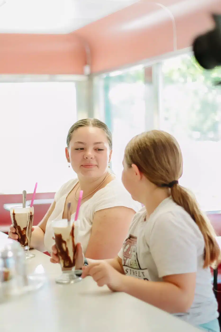 Two girls with chocolate milkshakes at the counter of the Oasis Diner in downtown Plainfield
