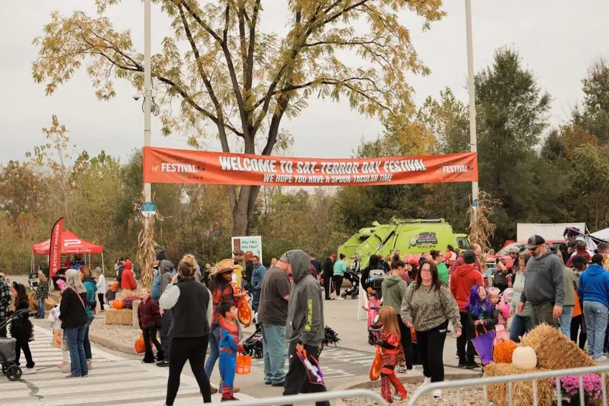 Families in Halloween costumes under the welcome banner at Plainfield's Sat-Terror Day festival